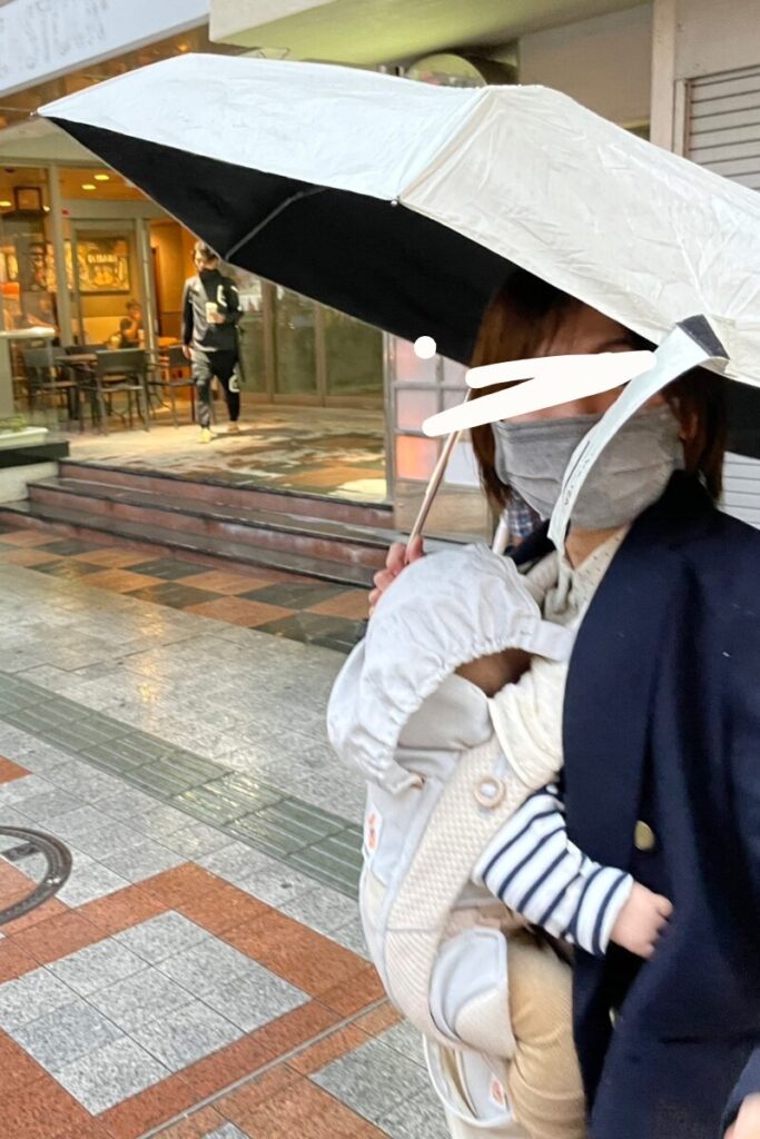 赤ちゃん連れ沖縄旅行中の突然の雨。抱っこ紐に折りたたみ傘で対応する写真。